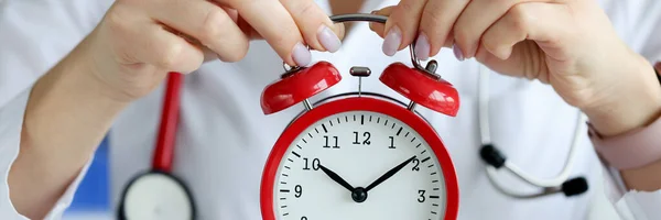 Doctor holding red alarm clock in clinic closeup — 스톡 사진