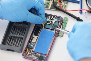 Technician fixing broken mobile phone, set new battery and cover, return old cellphone to life