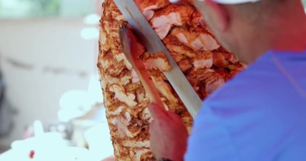 Chef cuts grilled chicken meat from rotating spit and prepares traditional Turkish street food Doner Kebab — Stockvideo