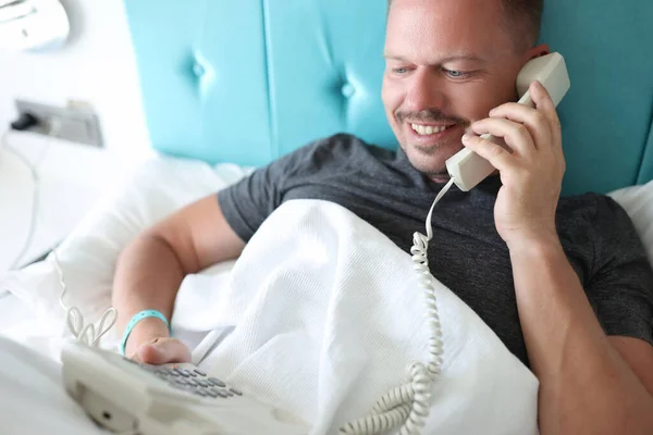 Smiling man calling on reception in hotel, want to order lunch in room —  Fotos de Stock