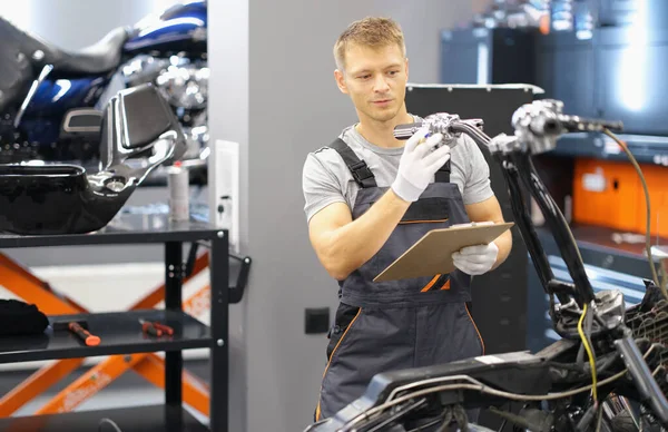 Maintenance service worker in uniform examine motorbike, man with clipboard paper — Foto Stock