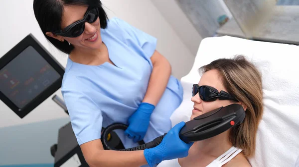 Beautician removing unwanted facial hair of client using laser in beauty salon — Zdjęcie stockowe