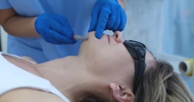 Güzellik uzmanı lazer tüy dökücü filmden önce sakallarını budayarak tıraş ediyor.