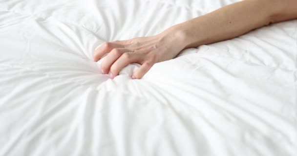 A nő keze szorosan összenyomja a lepedőt az ágyban — Stock videók