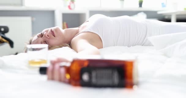 Sömnkvinna med alkoholmissbruk liggande i sängen med flaska whisky — Stockvideo