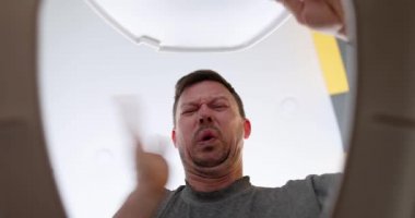 Adam pis kokulu ve pis kokulu tuvalet kapağını açar ve kanalizasyonu temizler.