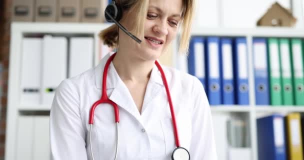 Лікар в навушниках з мікрофонами консультує пацієнта дистанційно — стокове відео