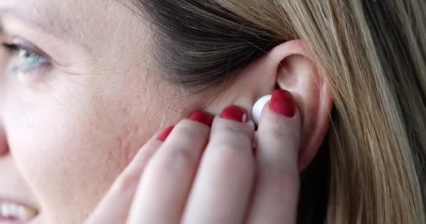 Smiling woman inserting wireless trendy earphones into ear — Vídeo de Stock