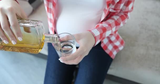 Mujer embarazada vierte bebida alcohólica en el vaso — Vídeo de stock