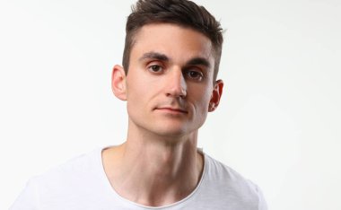 Young man with serious look, brunette man pose on white background