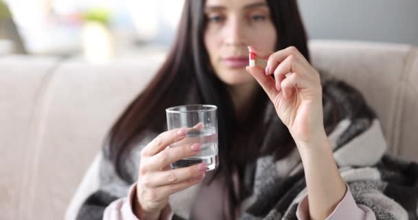 Sjuk kvinna håller medicin kapslar och glas vatten närbild 4k film — Stockvideo