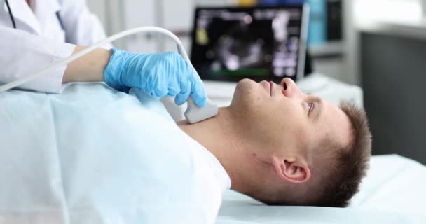 Лікар проводить ультразвукове обстеження щитовидної залози для пацієнта чоловічої статі в клініці 4k film slow motion — стокове відео
