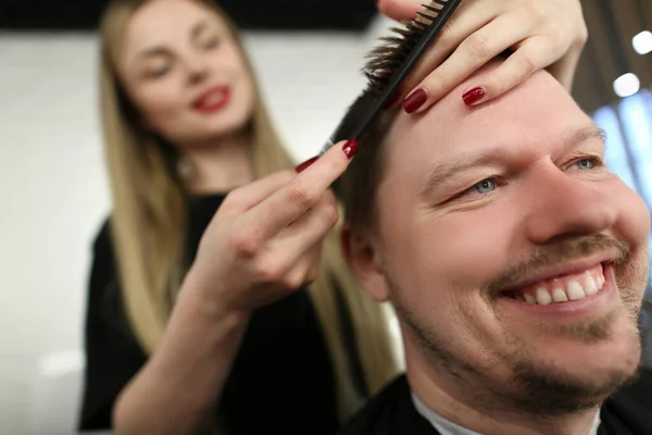Parrucchiere professionista femminile che taglia i capelli con le forbici, sorridente cliente maschile seduto sulla sedia master — Foto Stock