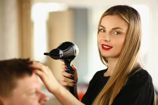 Blonde hairdresser using hairdryer to dry clients hairstyle, new image for man — Stock fotografie