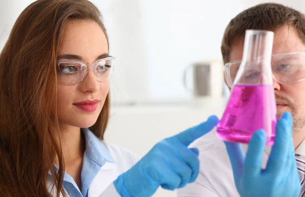 Smart scientists perform experiment in laboratory, bright pink liquid in glass — Photo