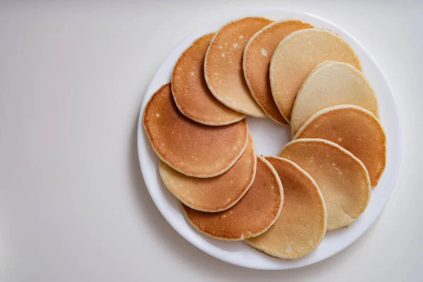 Lot of delicious appetizing pancakes lying on white plate in circle top view — Stock Photo, Image