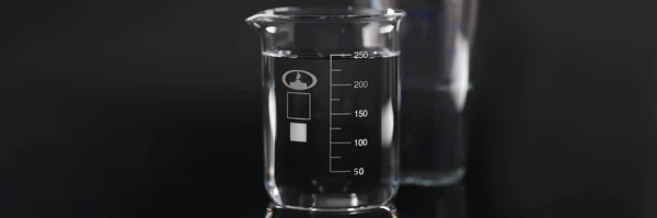 Gros plan de bécher chimique avec de l'eau sur fond noir — Photo