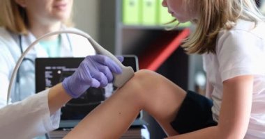 Çocuk filminde diz eklemini ultrasonla muayene eden doktor.