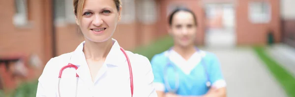 Kadın doktor ve hemşire kliniğin yakınında durun. — Stok fotoğraf