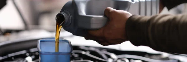A man pours oil into the car from a canister — Stock Photo, Image