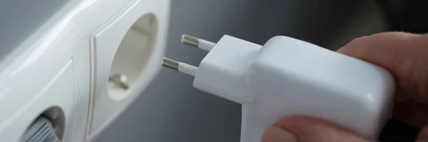 Hands plugging the charger into an outlet in the wall, close-up — Stock Photo, Image