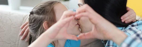 Mãe beijos pequena filha, juntos mostrar gesto do coração — Fotografia de Stock