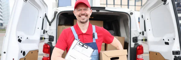 Uśmiechnięty mężczyzna trzymający pudełko i dokument dostawy — Zdjęcie stockowe