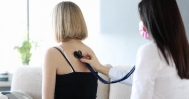 Kadın doktor, hastayı steteskopla dinler. Ev ziyareti sırasında kalp atışlarını ve akciğerlerini inceler.