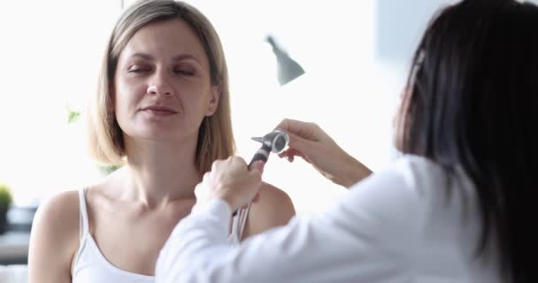 ЛОР проводит медицинское обследование уха пациента с помощью отоскопа — стоковое видео