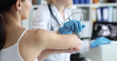 Doktor, klinikte hastanın dirseğini ultrasonla muayene ediyor.