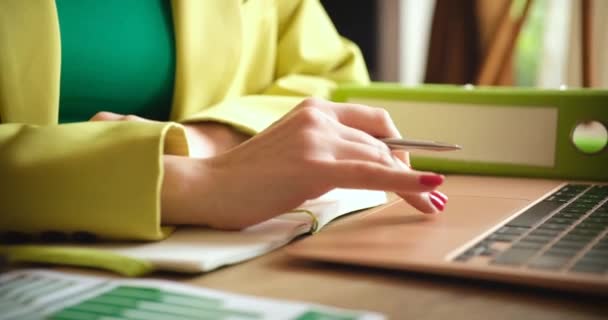 Business womans hands working on laptop and taking notes in notebook — Stock Video