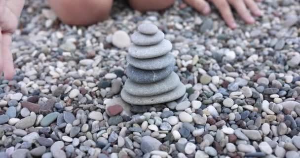 Детская рука разрушает каменную башню на пляже крупным планом 4k фильм замедленной съемки — стоковое видео