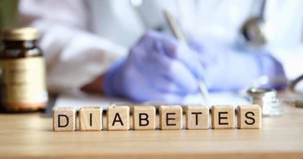 Doktor endokrinolog psaní ven předpis na pozadí dřevěných kostek se slovem diabetes detailní 4k film — Stock video