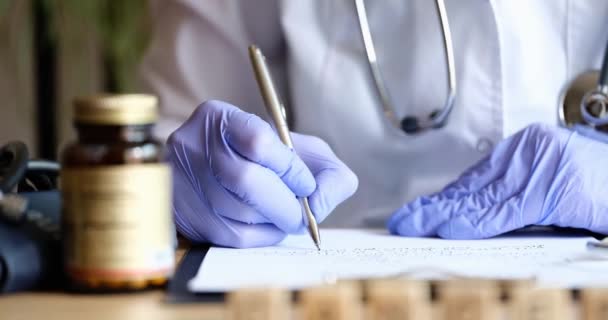 Médico en guantes escribiendo en documentos médicos en la mesa de primer plano película 4k — Vídeos de Stock