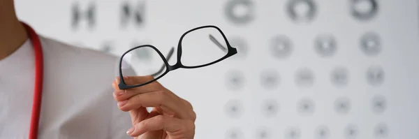 Жінка-лікар офтальмолог показує окуляри, крупним планом, розмиті — стокове фото