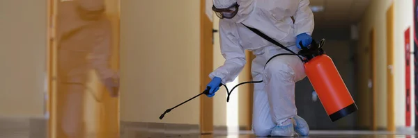 A man in a protective suit splashes on the plinth in the hallway — Stock Photo, Image