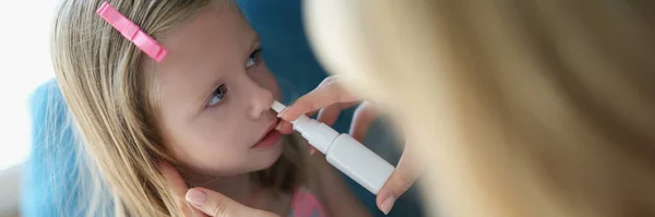Mamma sprayer babys nese med spray – stockfoto