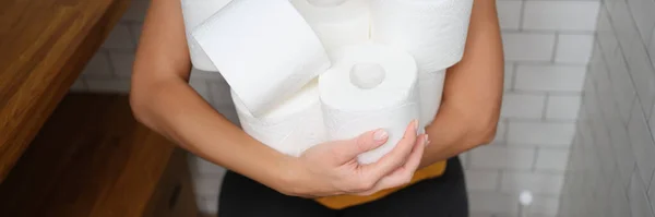 Женщина сидит на унитазе с рулонами туалетной бумаги — стоковое фото