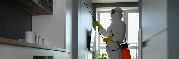 Um homem de fato de proteção pulveriza um apartamento — Fotografia de Stock