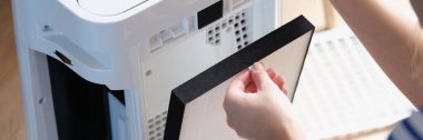 Hava arındırma sistemindeki filtreyi değiştiren kadın