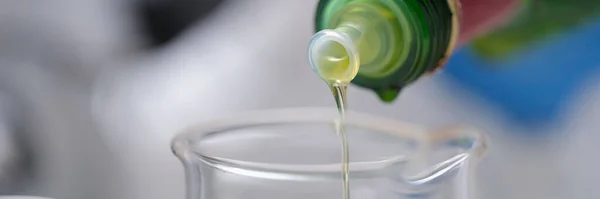 El aceite de una botella se vierte en un recipiente de medición —  Fotos de Stock
