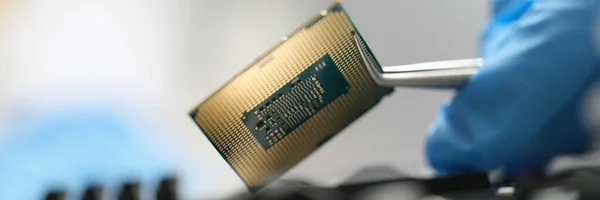 De master houdt een chip over het apparaat met een pincet, close-up — Stockfoto