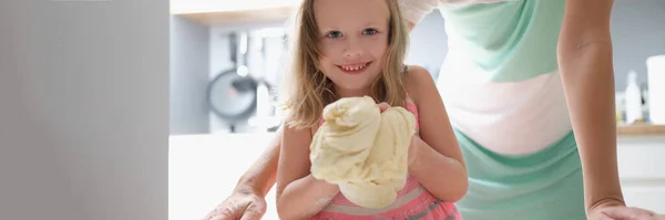 Little girl shows the dough and smiles — Stock Photo, Image