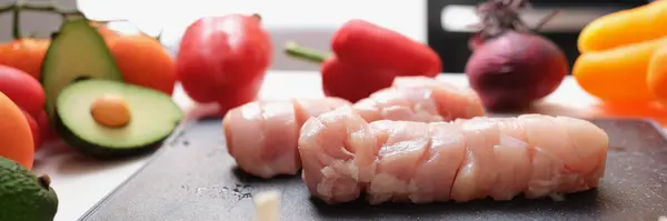 Mięso z kurczaka na desce do krojenia i warzywa na stole — Zdjęcie stockowe