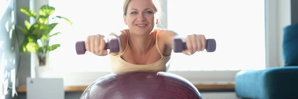 Woman doing exercises with dumbbells on a sports ball — Stock Photo, Image