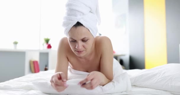 Χαμογελώντας όμορφη γυναίκα σε λευκό μπουρνούζι βρίσκεται μόνη της στο κρεβάτι στο υπνοδωμάτιο με τεστ εγκυμοσύνης — Αρχείο Βίντεο