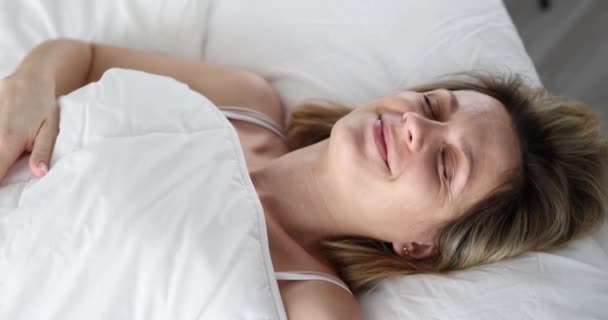 Spící žena vypadá vyděšeně pod přikrývkou v ložnici — Stock video