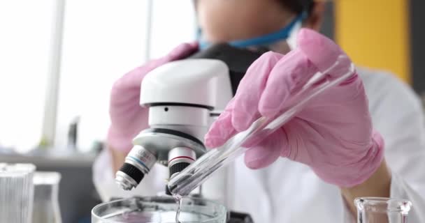 科学家化学家从试管中将粉红液体倒入显微镜下检查 有毒液体概念的发展 — 图库视频影像