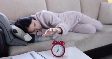 Kanepede uyuyan kadın çalar saati kapatır. Uykusuzluk, yorgunluk ve duyarsızlık.