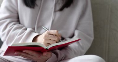 Kadın elleri evdeki kanepede günlüğe notlar yazar. Gazeteci mesleği veya günlük konseptine kişisel girdiler